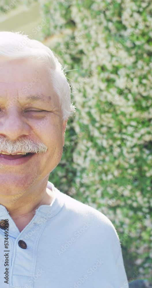 Vertical video half portrait of senior caucasian man smiling in garden, copy space, slow motion Vertical video half portrait of senior caucasian man smiling in garden, copy space, slow motion
