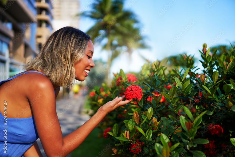 young Brazilian woman delicately holds a flower and approaches to smell its aroma on the street of Ipanema young Brazilian woman delicately holds a flower and approaches to smell its aroma on the street of Ipanema