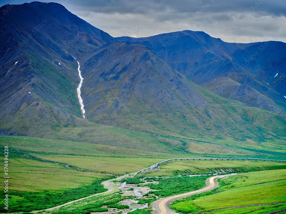 Summertime along the Dalton Highway North of the Coldfoot Camp on the road to Prudhoe Bay with the Alaska Pipeline dipping underground to protect the permafrost