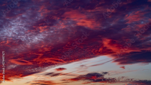 Sunset sky. Cirrocumulus and cirrostratus clouds during sunset. Beautiful dramatic sunset sky background. Selective focus included. Noisy photo.