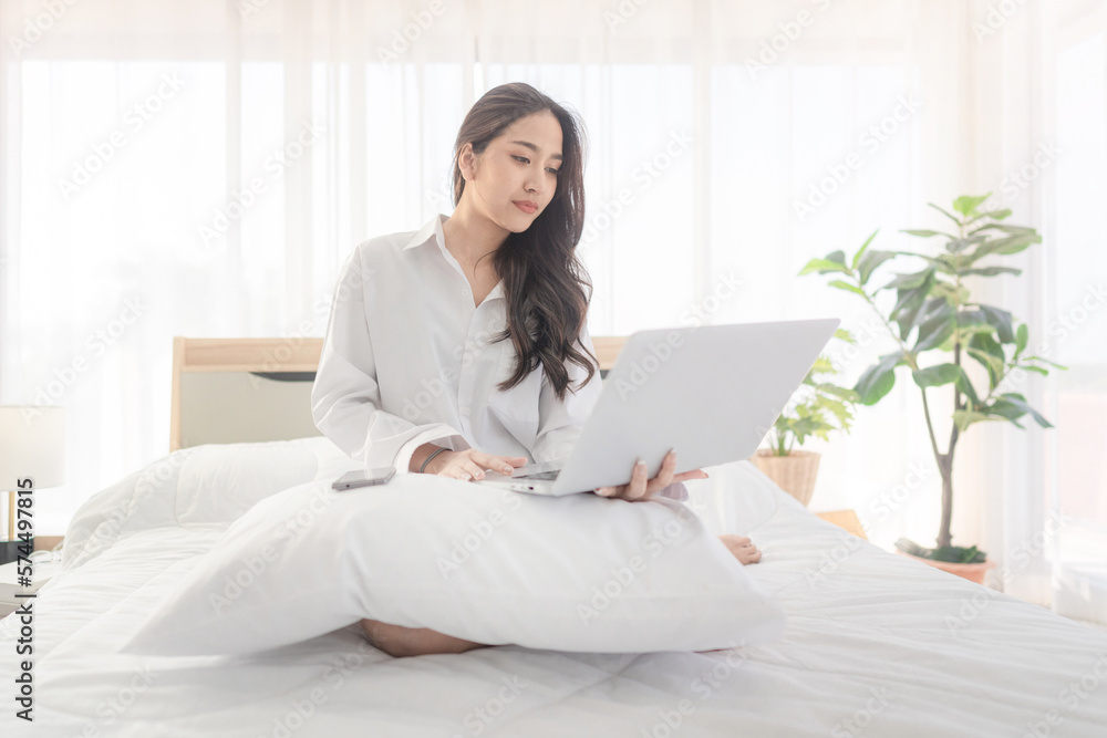 young asian woman using laptop when sitting on a bed. Smart living with ...