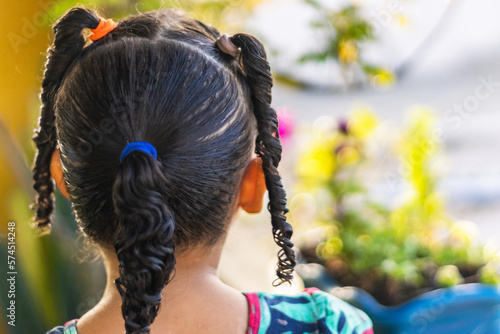 Little girl from the back in the garden with ponytail in her hair, or braids blurred background in bokeh, girl from the back with pigtail in her hair, rear view, brazilian girl from the back