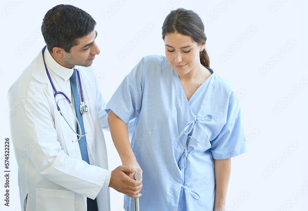 Middle Eastern doctor helping young female patient with crutches while walking. Middle Eastern doctor helping young female patient with crutches while walking.