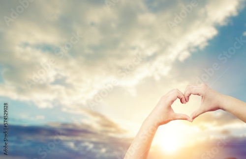 Human hands in heart shape on sky background