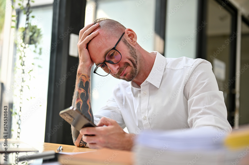 Failure and frustrated Caucasian businessman reading messages on his smartphone Failure and frustrated Caucasian businessman reading messages on his smartphone