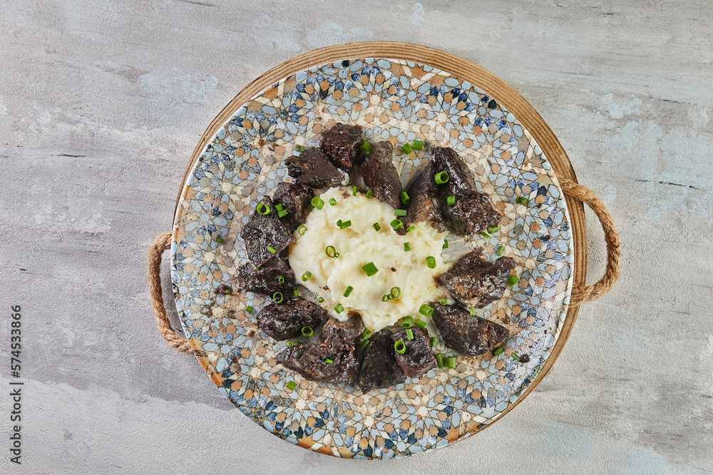 Chicken liver with mashed potatoes on plate on concrete background