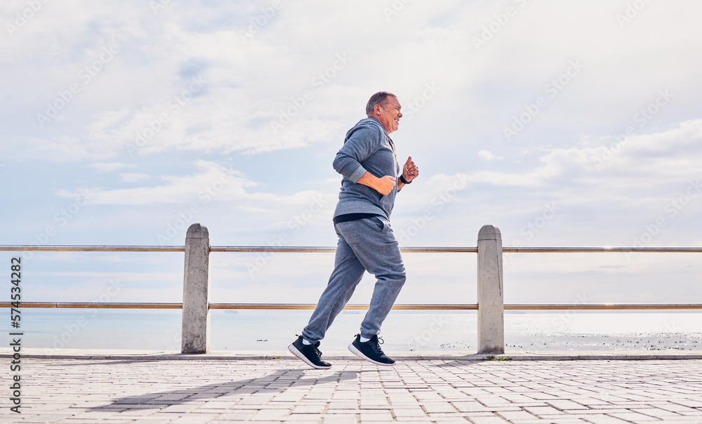 Senior man running outdoor at beach promenade, sky mockup and energy for body, wellness and cardio workout. Elderly male, exercise and runner at seaside for sports training, fitness or healthy action