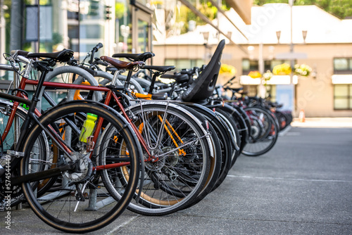 Various bicycles of college students of environmentalists stand in a row in a bicycle parking near the educational buildings