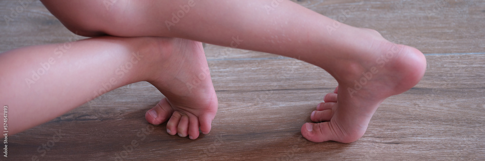 Children feet slide on wooden laminate at home closeup Children feet slide on wooden laminate at home closeup