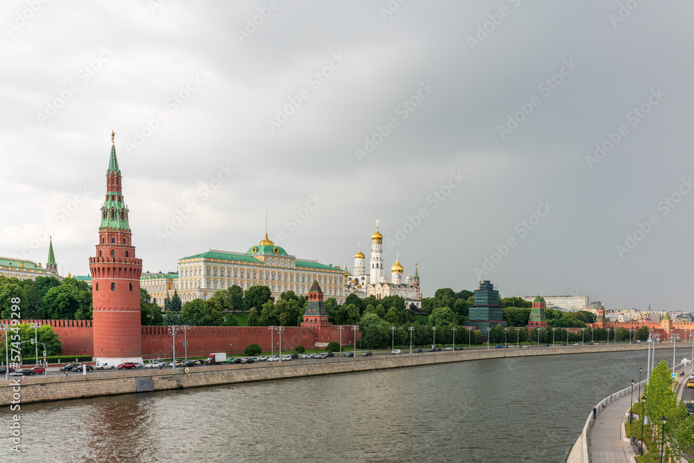 View of Kremlin with Vodovzvodnaya tower, Grand Kremlin Palace from repaired Bolshoy Kamenny Bridge in Moscow city on sunny summer day. Cruise ship sails on the Moscow river