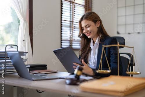 Attractive young lawyer in office Business woman and lawyers discussing contract papers with brass scale on wooden desk in office. Law, legal services, advice, Justice and real estate concept photo