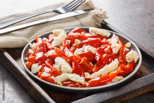 Esgarraet Red pepper and cod salad is a typical Valencian dish closeup on the plate on the wooden board. Horizontal photo