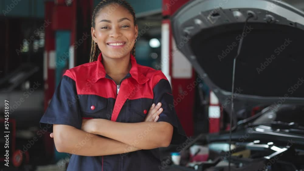Auto service, repair, maintenance concept. Mechanic checks the car at the service station.African american woman looking at camera engineer use tablet check car battery ... Auto service, repair, maintenance concept. Mechanic checks the car at the service station.African american woman looking at camera engineer use tablet check car battery ...