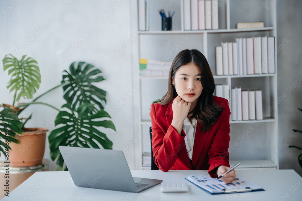 Confident Asian woman with a smile standing holding notepad, tablet and tablet at the modern home office. Confident Asian woman with a smile standing holding notepad, tablet and tablet at the modern home office.