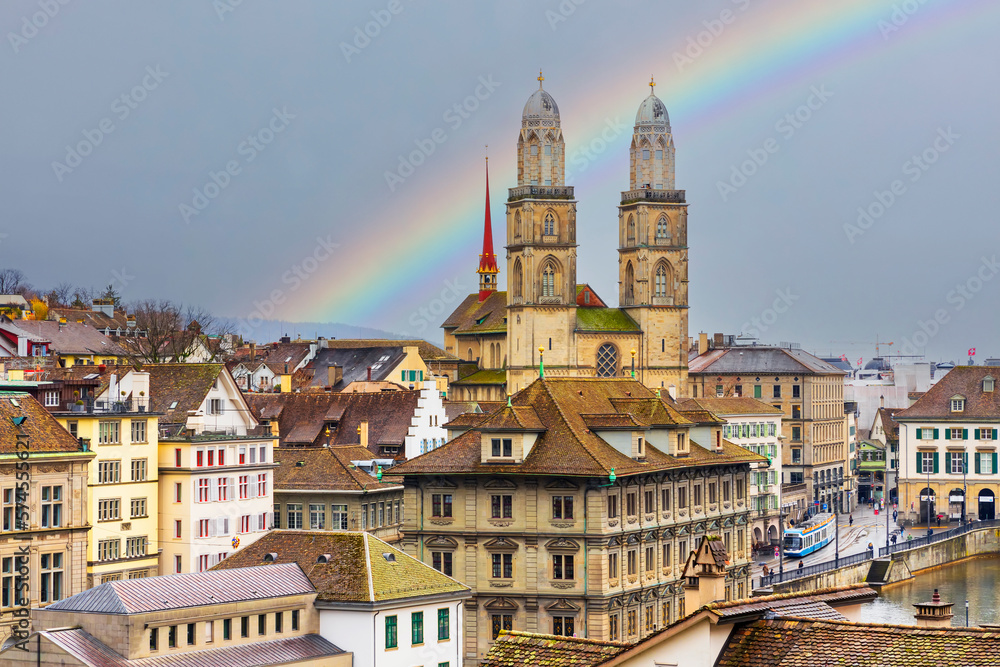 Grossmunster church in the center of Zurich city.Old town landscape of Grossmunster cathedral, Switzerland.Cityscape of Zurich in the rainy season with a rainbow over a cloudy grey sky.Tram in photo.