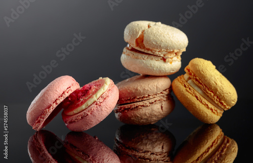 Delicious colorful macaroons on a black reflective background.