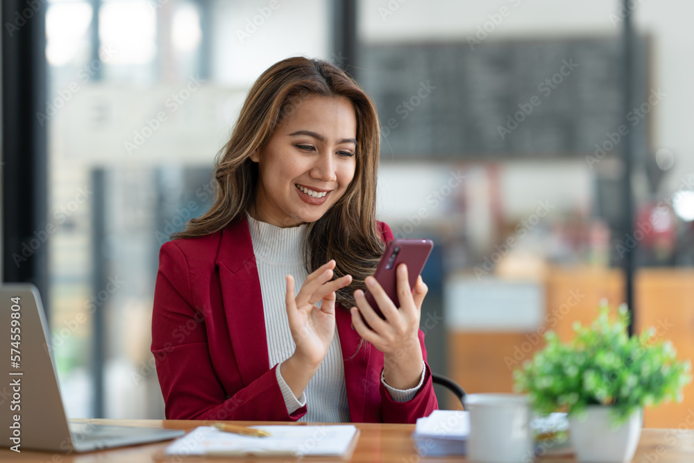 Beautiful asian businesswoman working with laptop computer is using mobile phone for talking. Finance business contacts in real estate projects in her office. Beautiful asian businesswoman working with laptop computer is using mobile phone for talking. Finance business contacts in real estate projects in her office.