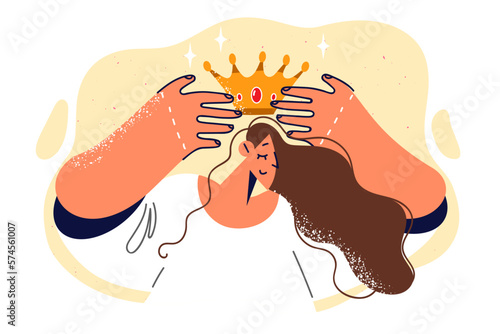 Woman closes eyes and puts golden crown on head to demonstrate status and ambitions