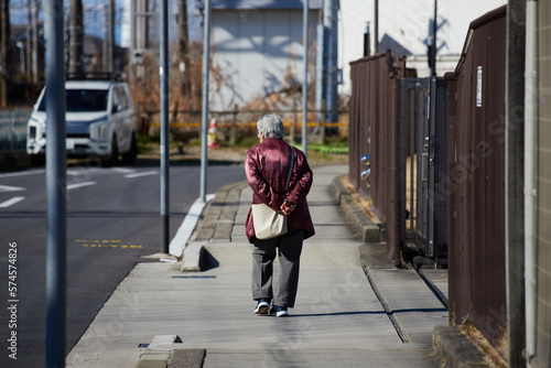 冬の日本の住宅地で散歩しているシニア女性の後ろ姿