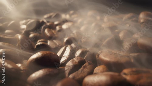 Process of roasting coffee beans. Smoke comes from fresh coffee seeds.Sliding shot of roast coffee beans with smoke on dark background