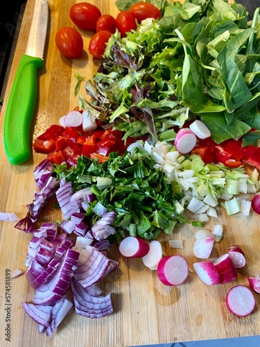 Salad greens tomatoes basil onions raddish on cutting board