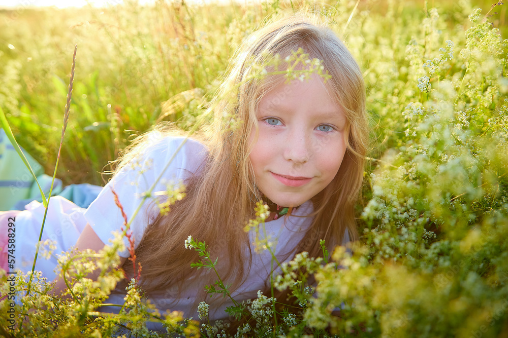 Portrait of pretty blonde girl having fun in a meadow on a natural landscape with grass and flowers on a sunny summer day. Portrait of a teenage child in summer or spring outdoors on field Portrait of pretty blonde girl having fun in a meadow on a natural landscape with grass and flowers on a sunny summer day. Portrait of a teenage child in summer or spring outdoors on field
