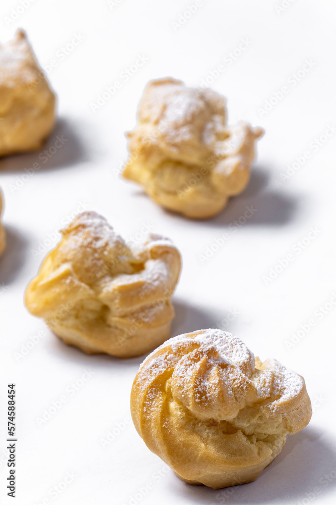 Decorating profiteroles with powdered sugar. Eclairs with icing sugar
