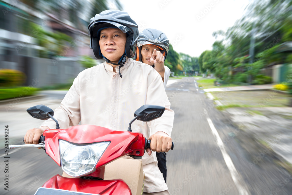 Asian Muslim family carrying a box on a motorcycle going mudik