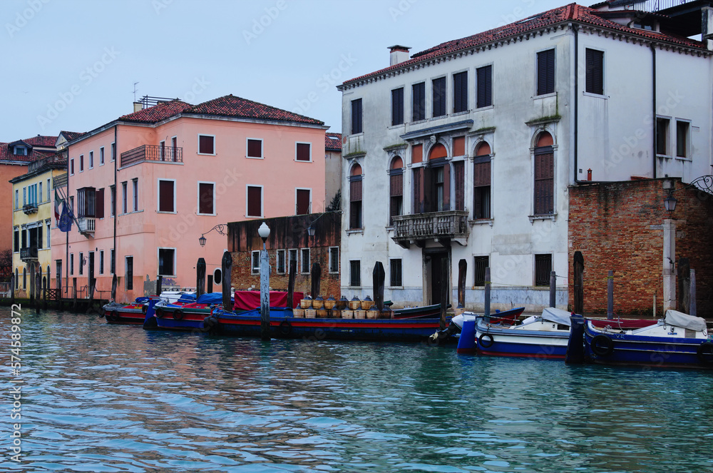 Cargo boats with goods are moored near ancient buildings. Transportation of goods by water. Cargo transportation in the city of Venice Winter drizzle morning in Venice