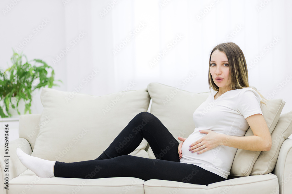 Facial expression of pregnant woman on white sofa. Facial expression of pregnant woman on white sofa.