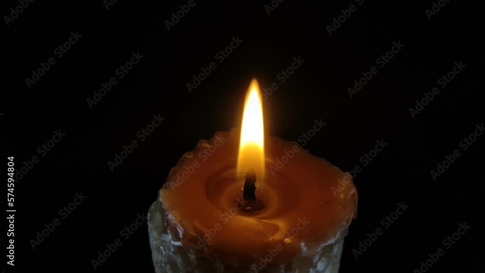 Man extinguishes the flame of a burning candle isolated on a black background Man extinguishes the flame of a burning candle isolated on a black background