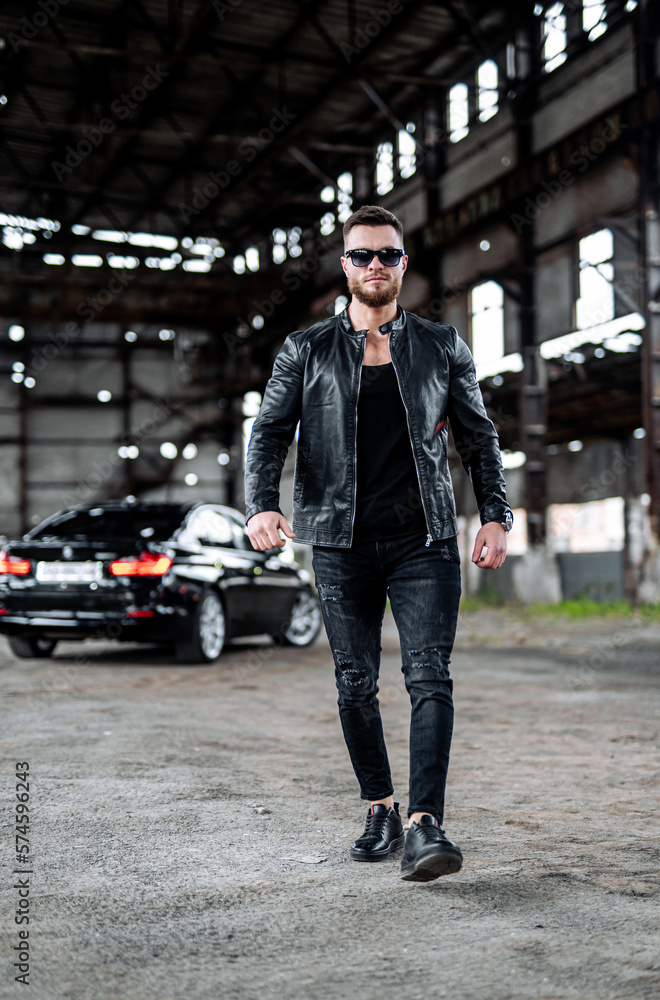 Obraz premium Man in dark glasses and black jacket. Brutal man in leather jacket with gun.