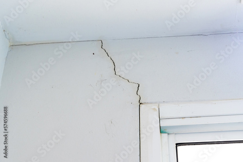 Wall crack near window frame in house or office interior building. Wall concrete broken from structure foundation problem concept.