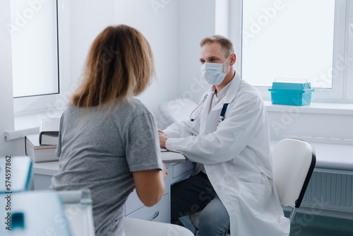 An appointment with a doctor at a clinic or medical center. The woman came to the doctor to establish the cause of the disease. Male therapist during work.