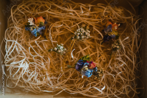 Kleine, bunte Blumensträuße liegen in einer Box mit Stroh als Polstermaterial. Die Sträuße sind kunstvoll gebunden und dekoriert photo