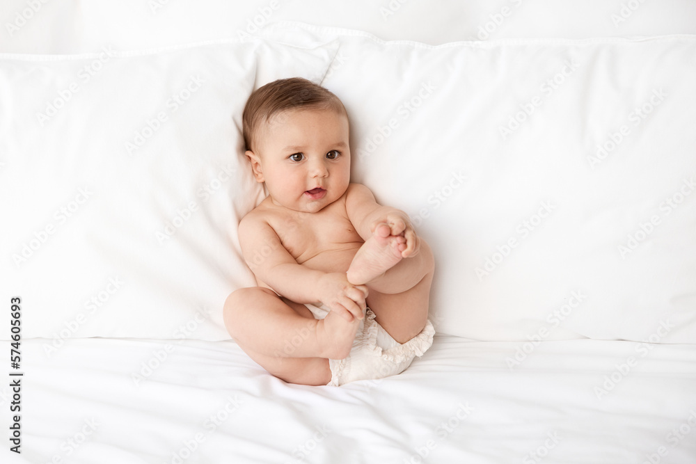 Young baby leaning against pillows holding feet Young baby leaning against pillows holding feet
