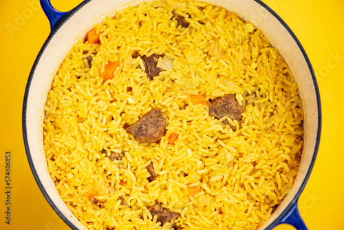 rice with meat in a pan, pilaf on a bright background