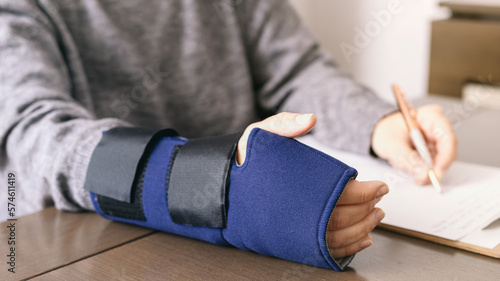 Crop injured person in fixing bandage writing on paper