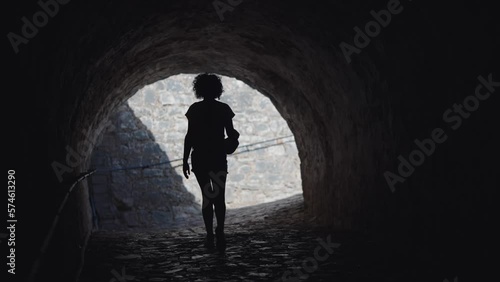 Tourist woman walking on underground pavement passage under New Venetian Fortress in Corfu, Greece, slow motion