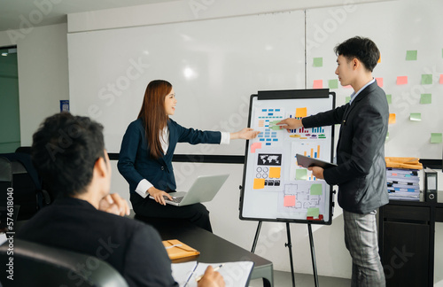 The boss stands near the board with graphs, demonstrates statistics, various personnel attending the training, introduces the new products of the company, in office.