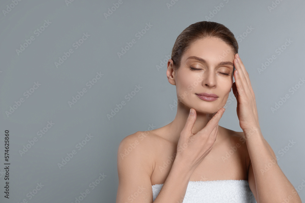 Woman massaging her face on grey background. Space for text Woman massaging her face on grey background. Space for text
