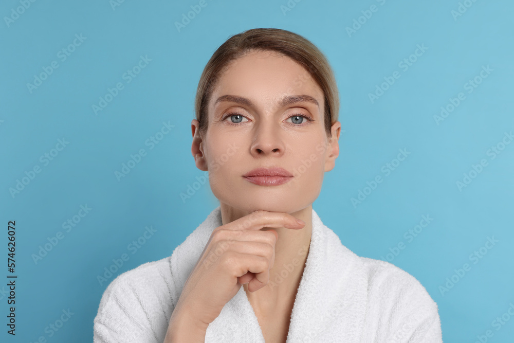 Woman massaging her face on turquoise background Woman massaging her face on turquoise background