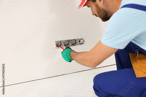 Wallpaper Mural Electrician with screwdriver repairing power sockets indoors Torontodigital.ca