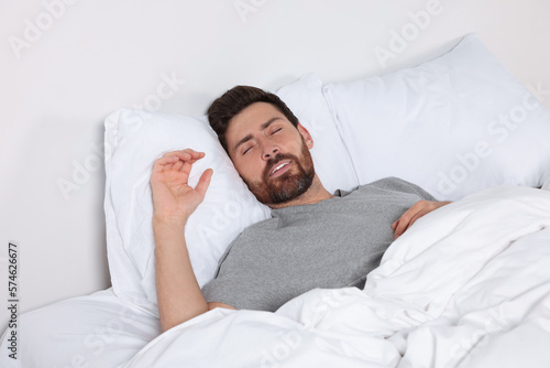 Man sleeping on comfortable pillows in bed at home © New Africa