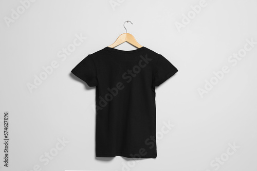 Hanger with black t-shirt on light wall. Mockup for design