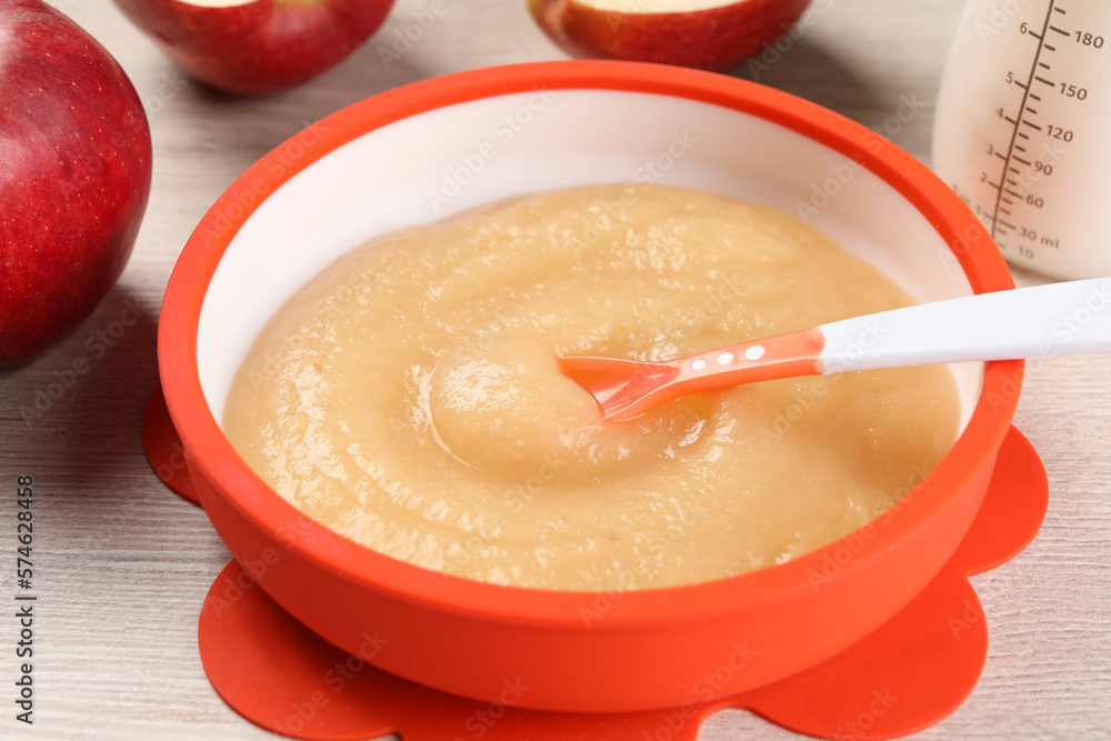 Healthy baby food. Bowl with delicious apple puree on white wooden table, closeup Healthy baby food. Bowl with delicious apple puree on white wooden table, closeup