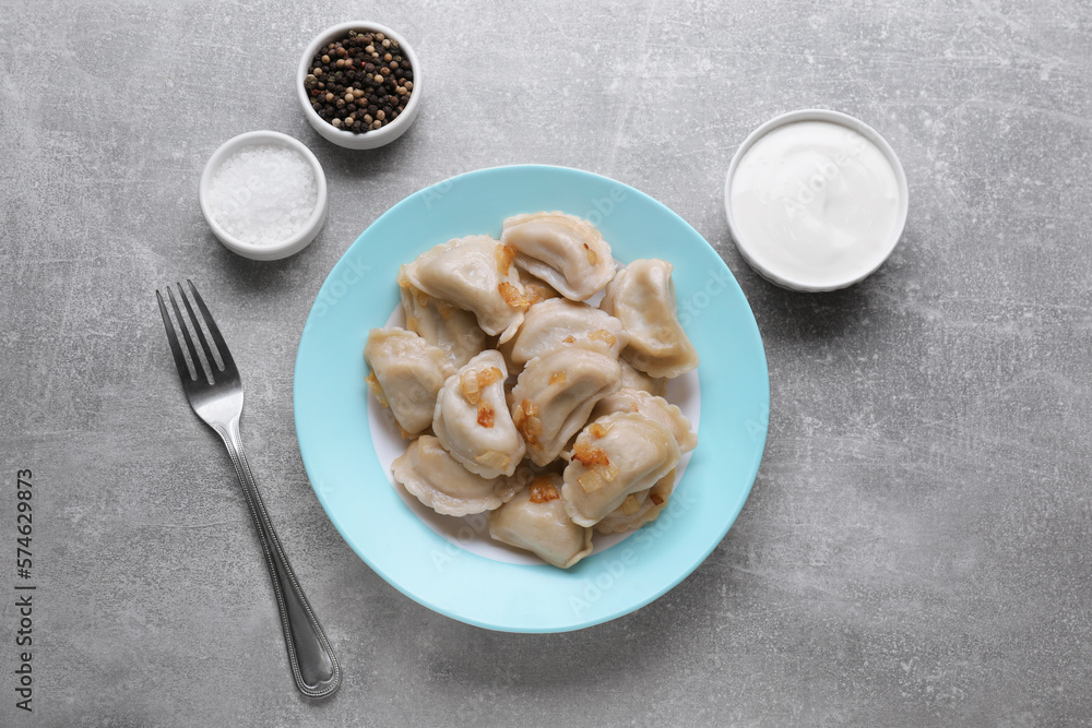 Delicious dumplings (varenyky) with potatoes and onion served on grey table, flat lay Delicious dumplings (varenyky) with potatoes and onion served on grey table, flat lay