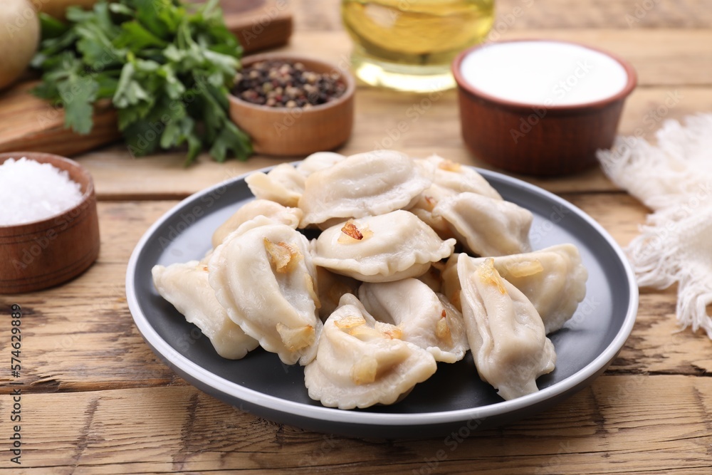 Delicious dumplings (varenyky) with potatoes and onion on wooden table Delicious dumplings (varenyky) with potatoes and onion on wooden table