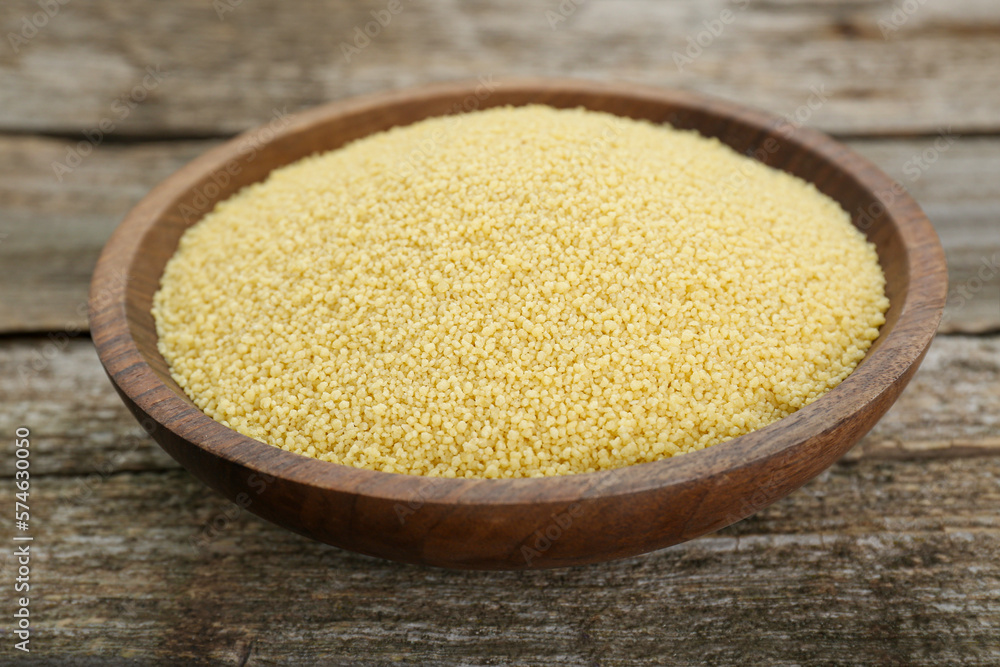 Bowl of raw couscous on wooden table, closeup Bowl of raw couscous on wooden table, closeup