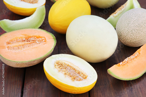 Different types of tasty ripe melons on wooden table